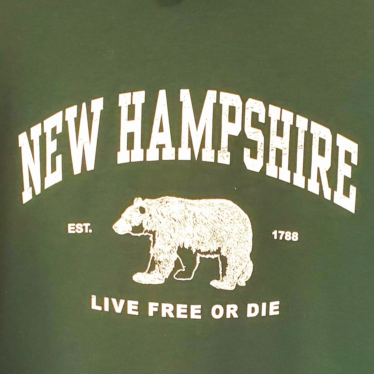 Green sweatshirt with white text and bear graphic, featuring 'New Hampshire' and 'Live Free or Die'.