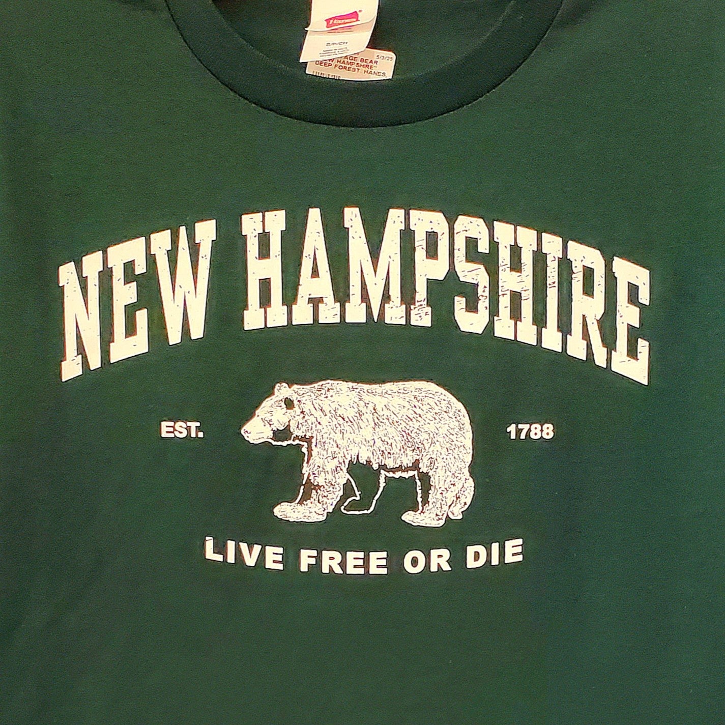 Green t-shirt with 'New Hampshire Live Free or Die' text and bear graphic.