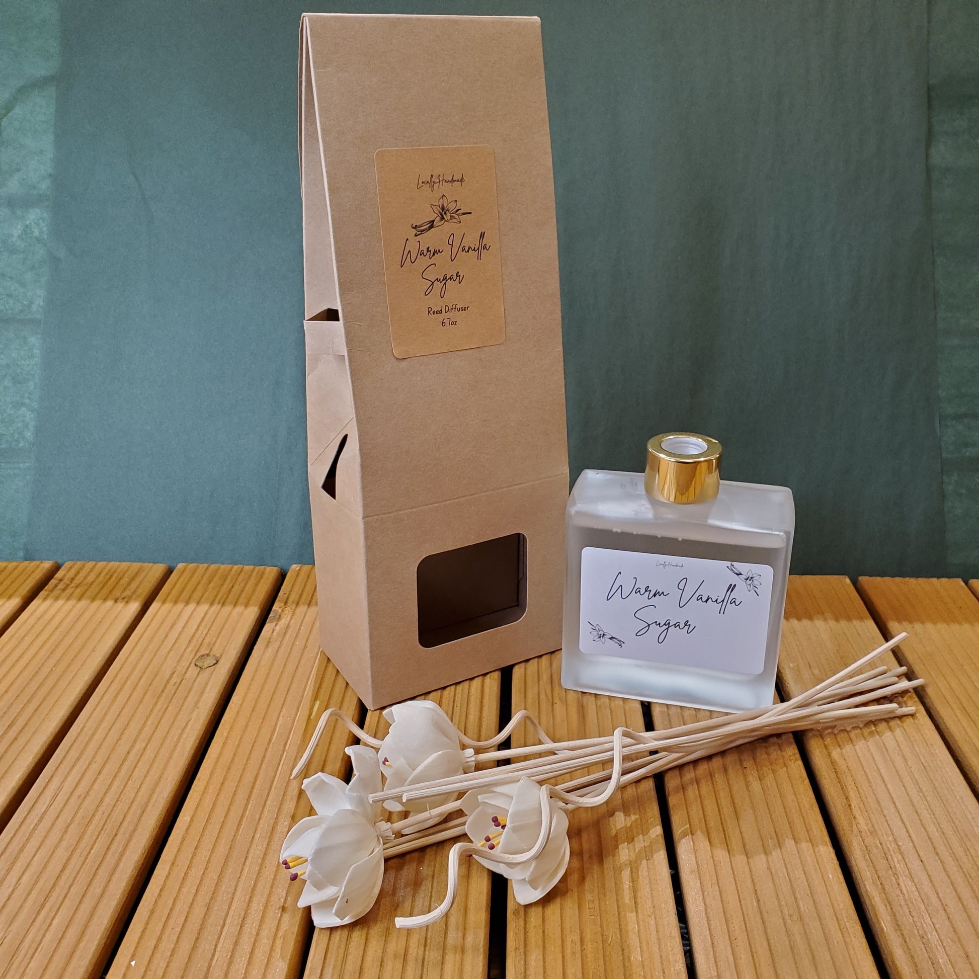 A bottle of perfume, a cardboard box, and a diffuser on a wooden surface.