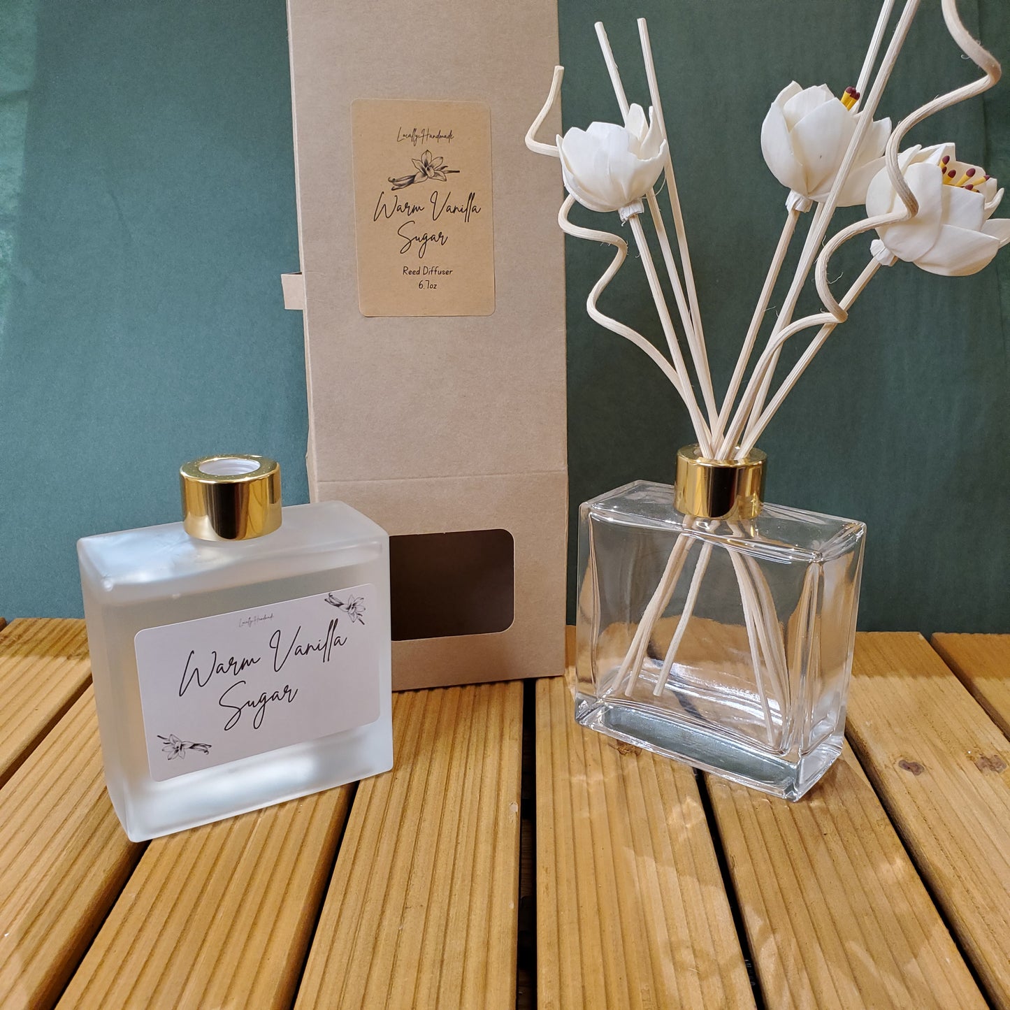 Two perfume bottles with floral diffusers on a wooden surface
