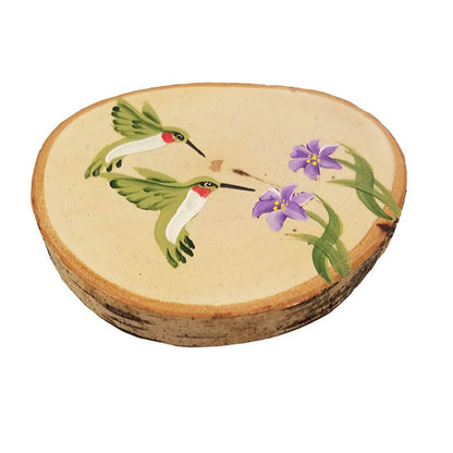 A round coaster made from a birch tree slice with a hand-painted hummingbird and flowers design, along with a cork backing.