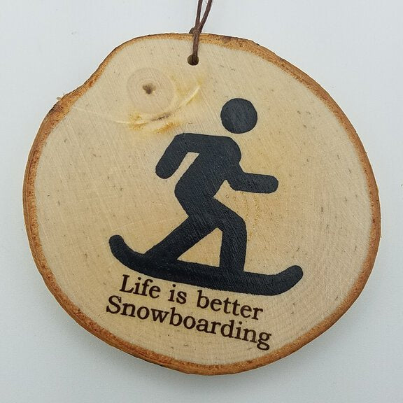 A round birch wood ornament with a snowboarder design and the text 'Life is better Snowboarding' engraved on it, with a string for hanging.