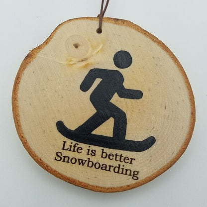 A round birch wood ornament with a snowboarder design and the text 'Life is better Snowboarding' engraved on it, with a string for hanging.