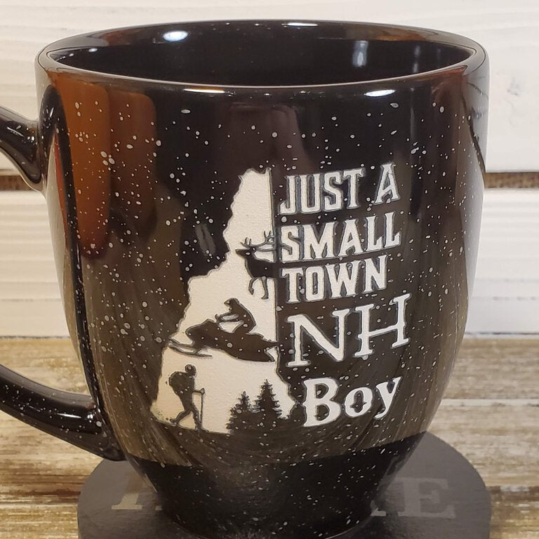 Black mug with 'Just a Small Town NH Boy' text and silhouette design on a wooden surface.